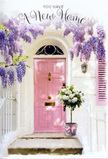 A quietly enchanting doorway in Ealing is styled as if to welcome its very first guests, bathed in soft natural light that seems to linger over every detail. The front door, painted in a gentle shade of pink, has a warm, inviting presence that might remind you of walking past pretty terraces near Haven Green or the tree-lined roads by Ealing Common. Around and above it, lush wisteria trails in generous cascades, each cluster of lavender blooms hanging like a fragrant curtain that softens the crisp lines of the whitewashed wall. The wall itself carries a faint texture, catching tiny shadows that shift as the light moves, giving the whole entrance a feeling of depth and quiet charm. At the doorstep, a grey metal bucket brims with an abundant arrangement of creamy white roses and fresh green foliage. The roses are plump and velvety, each petal unfurling in layers that suggest careful selection and expert conditioning by a skilled florist. Around the base of the bucket, a pale pink ribbon is tied in a loose, elegant bow, its colour echoing the door and binding the composition into a harmonious palette of blush, cream, and soft green. You can almost picture a new homeowner arriving, pausing to breathe in the delicate mix of rose and wisteria, the air cool and perfumed around them. The scene radiates quiet celebration and gentle optimism, perfectly suited to a housewarming delivery in Ealing, where flowers like these help transform an unfamiliar doorway into a place that already feels like home.